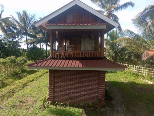 a small brick building with a balcony on a hill at Coconut Homestay Tetebatu in Tetebatu
