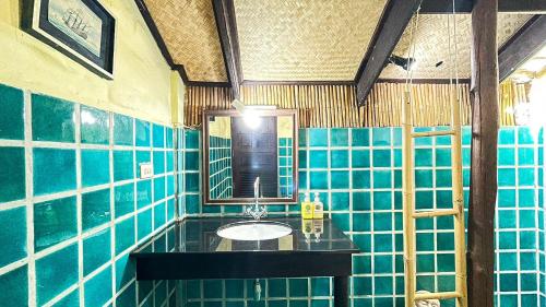 bagno piastrellato blu con lavandino e specchio di Villa Bali Eco Resort, Rayong a Rayong