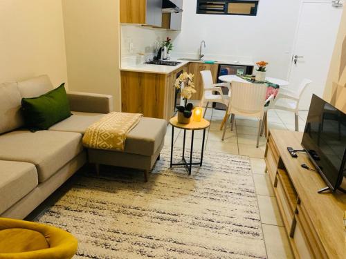 a living room with a couch and a kitchen at Nelly`s Green Creek Luxury Apartment in Pretoria