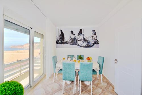 ein Esszimmer mit einem Tisch und blauen Stühlen in der Unterkunft Stone's Throw - Front line apartment in Nazaré in Nazaré