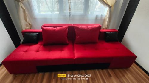 a red couch with red pillows in front of a window at Central City Park in Bacău
