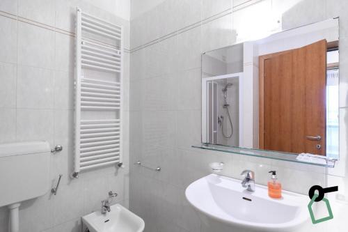 een witte badkamer met een wastafel en een spiegel bij HOTIDAY Residence Garda in Peschiera del Garda