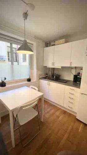 a kitchen with white cabinets and a table and a table and chair at Cozy Cottage In Central Gothenburg in Gothenburg