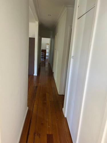 an empty hallway with wooden floors in an apartment at Gorgeous Master Bedroom with Own Bath in Frankston