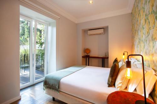 a bedroom with a bed and a large window at Casa Vela Boutique House in Cascais