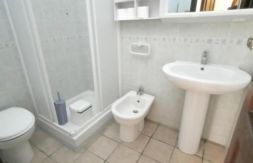 a white bathroom with a toilet and a sink at Villetta Bedogni in Simius