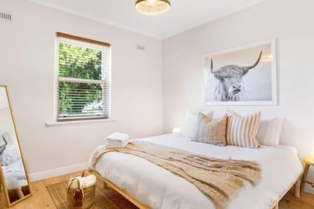 a bedroom with a bed with a picture of a cow on the wall at Rossini's Cottage - Hills Escape in Mount Lofty