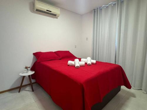 1 dormitorio con 1 cama roja y 2 toallas en Itaparica Beach Lindo Pé na Areia 02 Qtos Praia de Itaparica, en Vila Velha