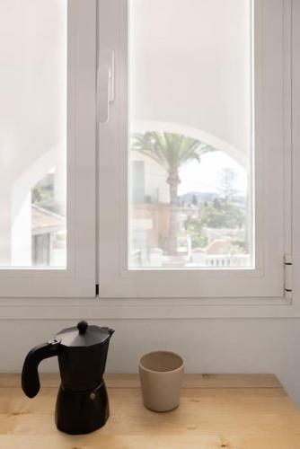uma chaleira de chá preto sentada numa mesa em frente a uma janela em Estudio Morera em Málaga