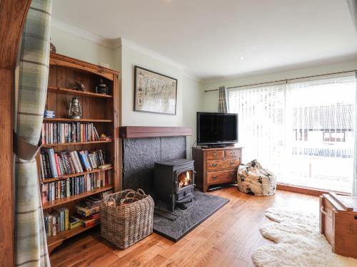a living room with a fireplace and a television at The Hideout in Portree