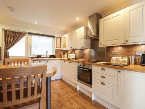 a kitchen with white cabinets and a wooden table at The Hideout in Portree