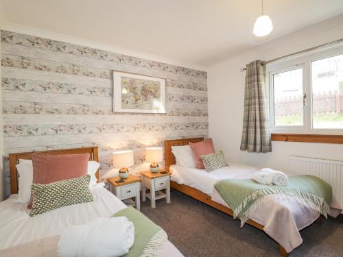 a bedroom with two beds and two windows at The Hideout in Portree