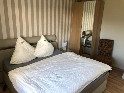 a bedroom with a bed with white sheets and pillows at Marbijes Appartementhaus in Cuxhaven