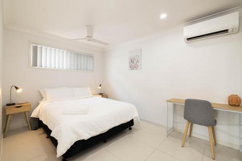 a white bedroom with a bed and a desk at Aircon! Parking! Host with 100s of 5 star Reviews! in Brisbane