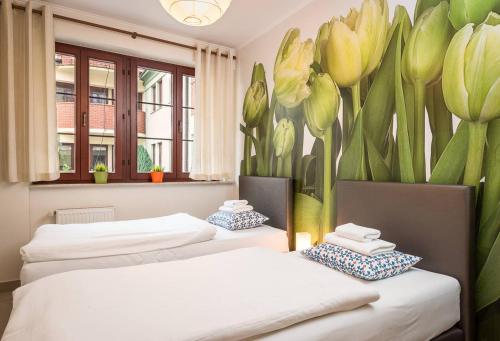 two beds in a room with flowers on the wall at LeoApart in Wrocław