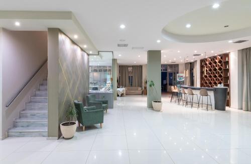 a lobby with a staircase and chairs and tables at Gouves Bay by Omilos Hotels in Gouves