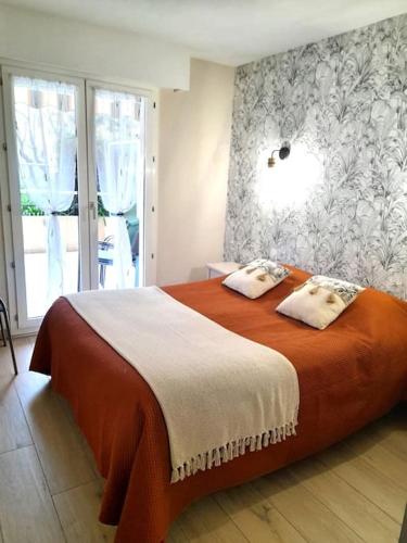 - une chambre avec un grand lit orange et des oreillers dans l'établissement En toute quiétude, Fréjus plage à 5min à pied, à Fréjus