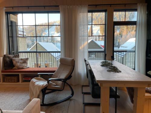 a living room with a table and chairs and windows at Ljungvind Funäsdalen in Funäsdalen
