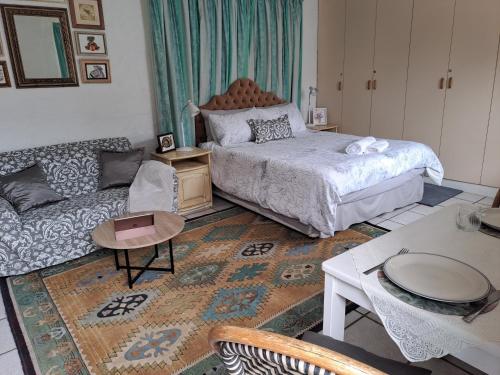 een woonkamer met een bed en een bank bij Watercolour Cottage in Hermanus