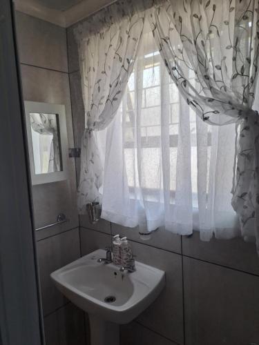 een badkamer met een wastafel en een raam bij Watercolour Cottage in Hermanus