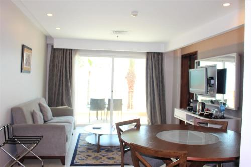 a living room with a couch and a table and a television at Mövenpick Hotel & Resort Al Bida'a in Kuwait