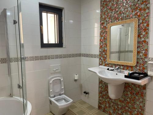 een badkamer met een wastafel, een toilet en een spiegel bij Hotel 5092 in Abuja