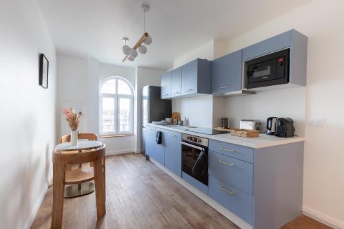 une cuisine avec des armoires bleues et une table dans l'établissement Appartement L3 ARENA Reims Gare Centre, à Reims