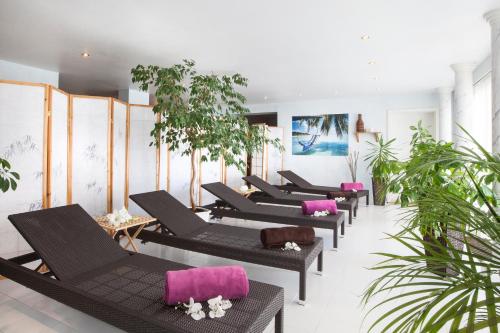 una fila di sedie a sdraio nere con cuscini rosa di Meeressterne Hotel Residenz in Heringsdorf a Heringsdorf