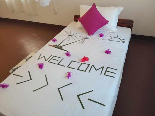 a bed with flowers on it with the word welcome at Laliz in Hikkaduwa