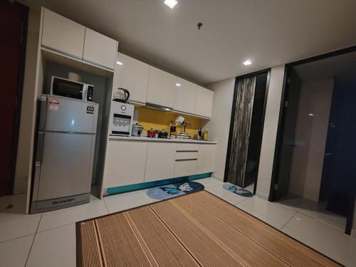 a kitchen with white cabinets and a refrigerator at Ber-Santai @Sky Hotel Suites in Kota Kinabalu
