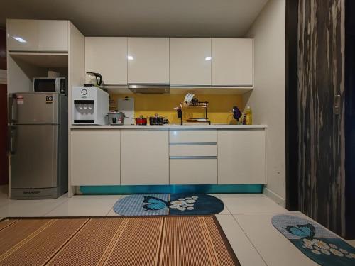 a kitchen with white cabinets and a refrigerator at Ber-Santai @Sky Hotel Suites in Kota Kinabalu