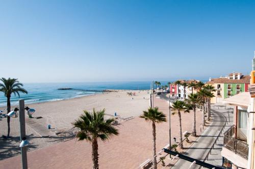 a view of a beach with palm trees and the ocean at HAPPYVILA Rustico Apartments in Villajoyosa