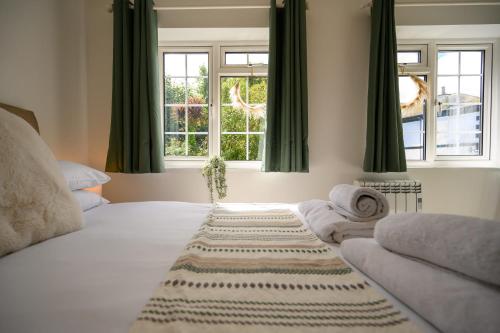 um quarto com uma cama branca e cortinas verdes em Coastal Haven Ilfracombe by StayStaycations em Ilfracombe