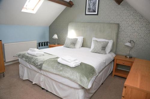 a bedroom with a large bed with two towels on it at The Maypole at Wellow in Ollerton