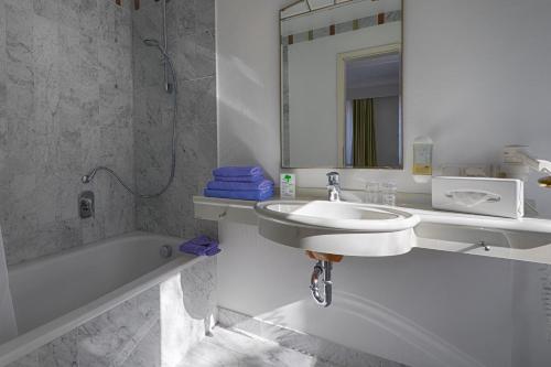 a bathroom with a sink and a tub and a mirror at Hotel Residenz in Heringsdorf