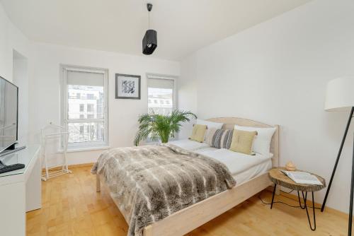 a white bedroom with a bed and a tv at Spacious & Bright Apartment with Parking Poznań by Renters in Poznań