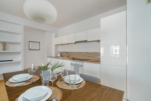 a kitchen with a table with plates and wine glasses at Spacious & Bright Apartment with Parking Poznań by Noclegi Renters in Poznań
