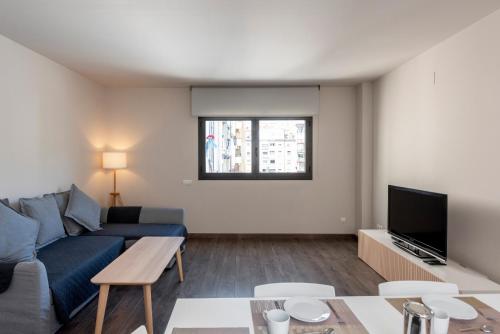 a living room with a blue couch and a tv at Espais Blaus Apartments in Barcelona