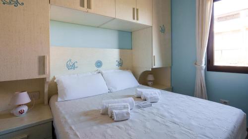 a bedroom with a large white bed with towels on it at Welcomely - Essenza Di Sardegna in Marinella