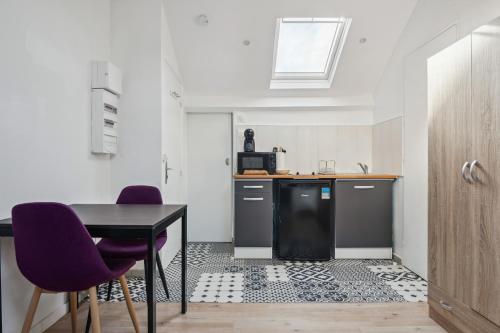 une cuisine avec une table et deux chaises violettes dans l'établissement Budget appart avec parking au centre-ville, à Charleville-Mézières