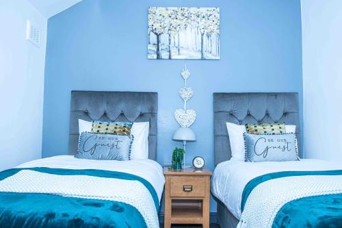Duas camas num quarto com paredes azuis em TD M-Gold Dudley Luxurious 3 Bedroom House - Sleeps 8 - Perfect for Leisure, Families, Business Long and Short Stay - Free Parking 