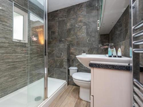 La salle de bains est pourvue de toilettes, d'un lavabo et d'une douche. dans l'établissement Pass the Keys Cosy Miners Cottage, à Telford