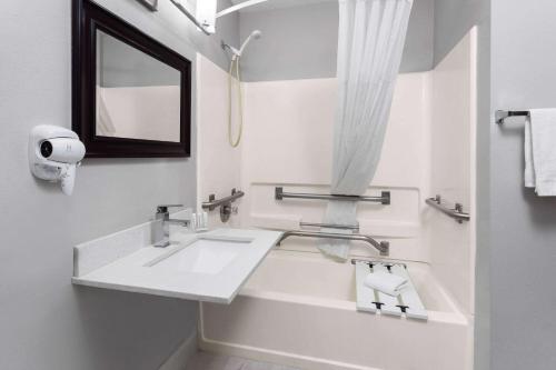 a white bathroom with a sink and a mirror at Days Inn & Suites by Wyndham Sellersburg in Sellersburg