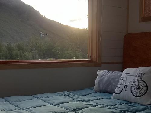 a bed with a pillow with a bicycle on it next to a window at LA CABAÑA DEL CAMPO in Ushuaia