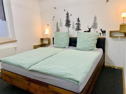 a bedroom with a bed with green sheets and trees on the wall at Forsthaus am Waldrand 