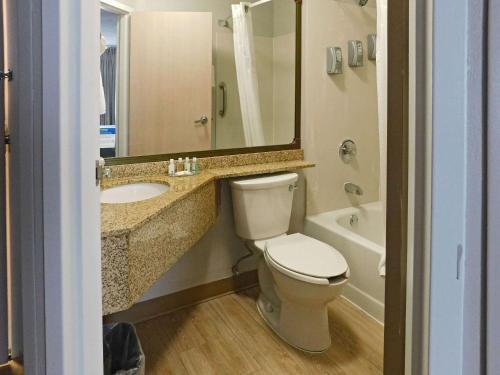 a bathroom with a toilet and a sink and a mirror at Quality Inn Colchester - Burlington in Burlington