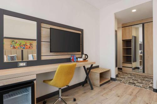 a room with a desk with a television and a chair at Ramada Encore By Wyndham Istanbul Basin Express in Istanbul