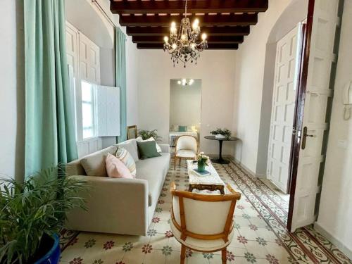 a living room with a couch and a chandelier at GINVA - Casa palacio La Templanza in El Puerto de Santa María