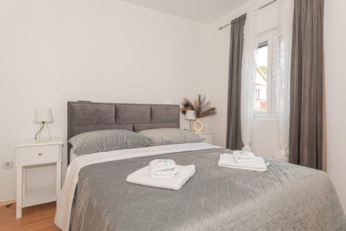 a white bedroom with two towels on a bed at Apartment Mozart in Šibenik