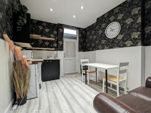 a kitchen and living room with a table and a clock on the wall at Inner-City Apartments - Basic Amenites in Cardiff